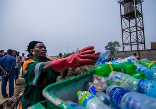 Woman in Lagos, Nigeria putting plastic waste into a bin. Credit: shynebellz / Shutterstock